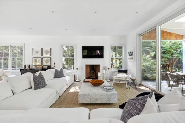 a living room with furniture a fireplace and a large window with garden view