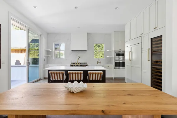 a kitchen with kitchen island a stove a refrigerator a sink dishwasher with a dining table and chairs