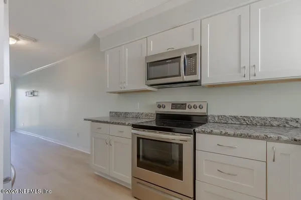 a kitchen with white cabinets and stainless steel appliances