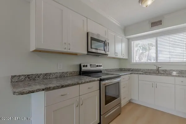 a kitchen with granite countertop white cabinets white stainless steel appliances and a sink