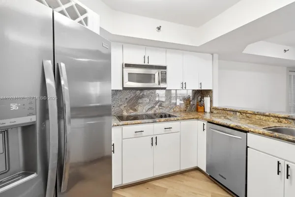 a kitchen with granite countertop a sink cabinets and stainless steel appliances