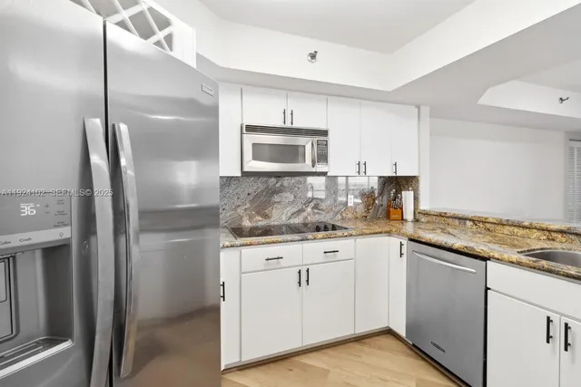 a kitchen with granite countertop a sink cabinets and stainless steel appliances