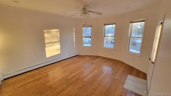 a view of empty room with wooden floor and fan
