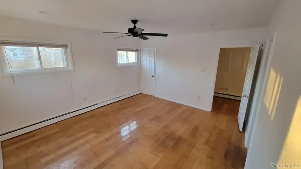 a view of empty room with wooden floor and fan
