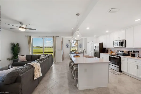 a large kitchen with stainless steel appliances kitchen island granite countertop a refrigerator a sink a stove and a dining table with white cabinets