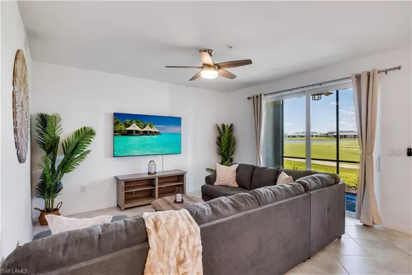 a living room with furniture a ceiling fan and a flat screen tv
