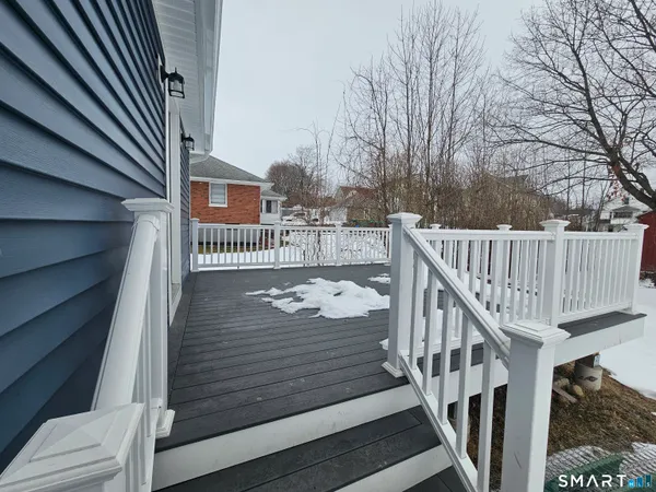 a view of balcony with wooden floor and fence and a couple of cars parked on road