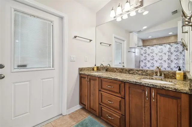 a bathroom with a granite countertop sink a mirror and a shower