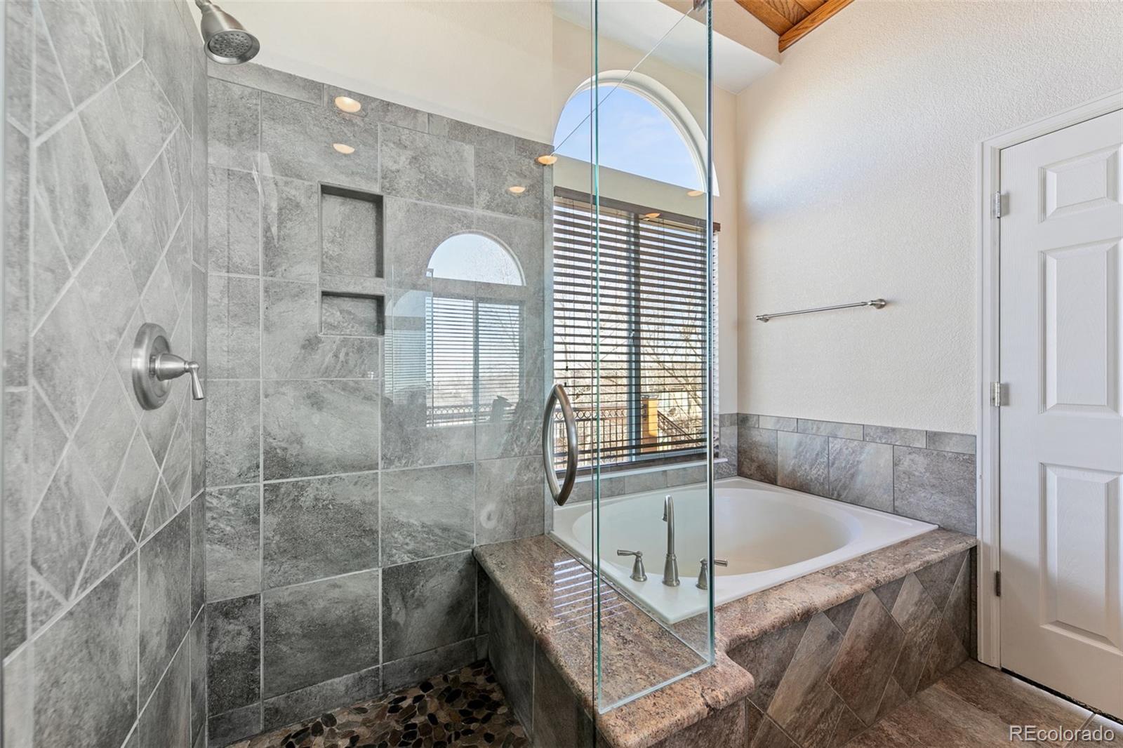 10072 Williams Way Thornton, CO 80229 - Photo 15 of 24 a bathroom with a tub a mirror and a shower