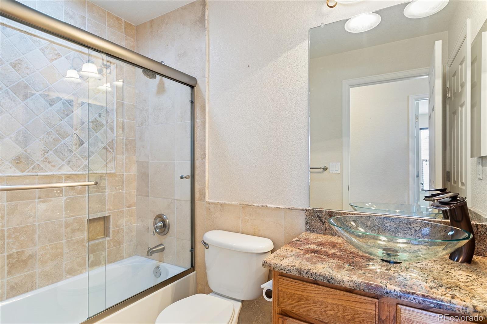 10072 Williams Way Thornton, CO 80229 - Photo 18 of 24 a bathroom with a granite countertop sink toilet and shower