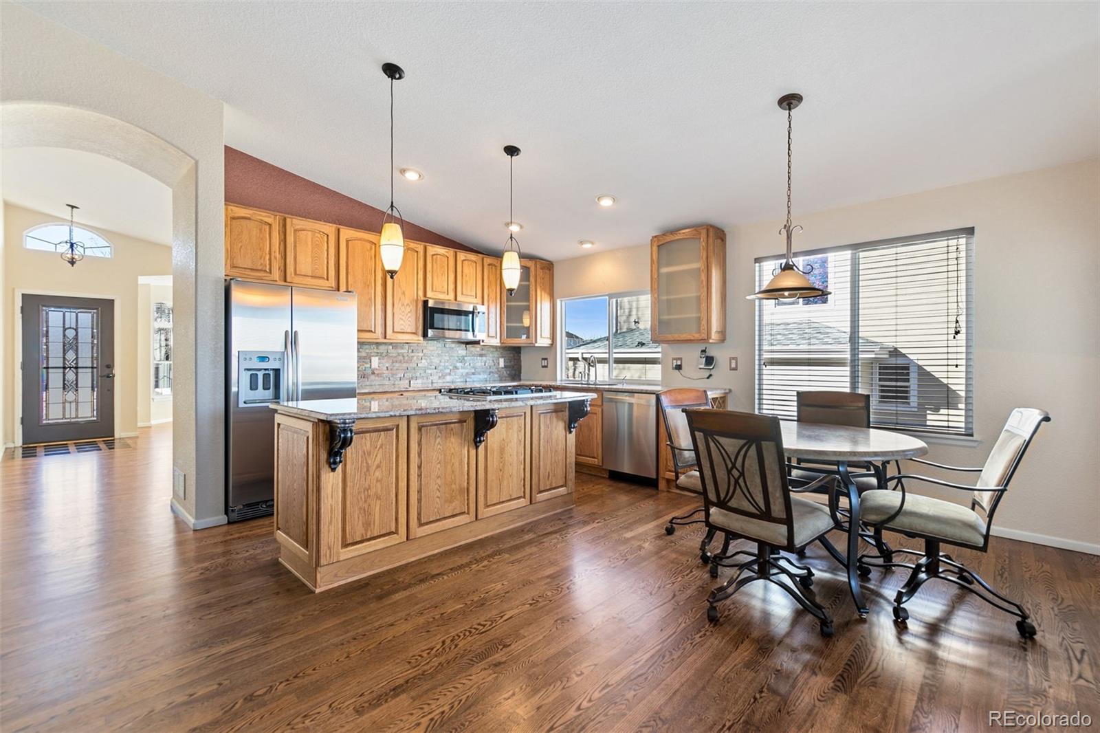 10072 Williams Way Thornton, CO 80229 - Photo 10 of 24 a kitchen with stainless steel appliances granite countertop wooden floors and white cabinets