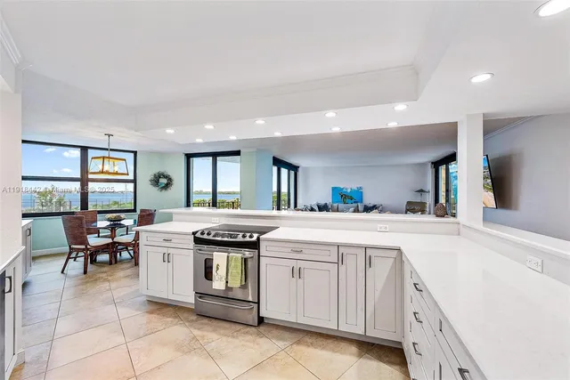 a kitchen with a stove a sink a refrigerator and chairs