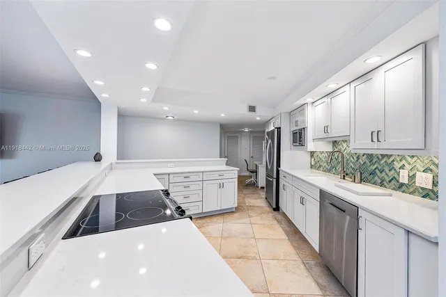 a large kitchen with stainless steel appliances a large counter top a stove a sink and a refrigerator