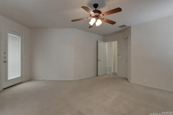 an empty room with a chandelier fan and windows