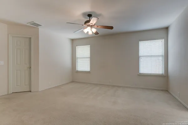 an empty room with windows and chandelier fan