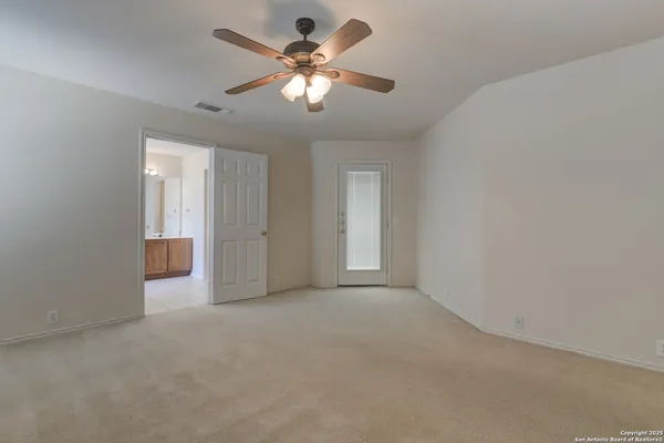an empty room with chandelier fan and windows