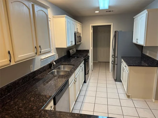 a kitchen with granite countertop a sink a stove and a refrigerator