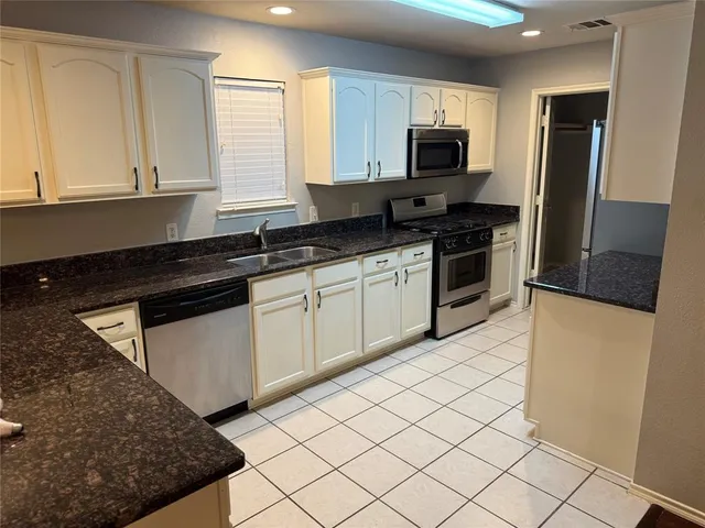 a kitchen with granite countertop a sink a stove top oven and refrigerator