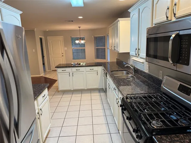 a kitchen with stainless steel appliances granite countertop a stove a sink and a microwave