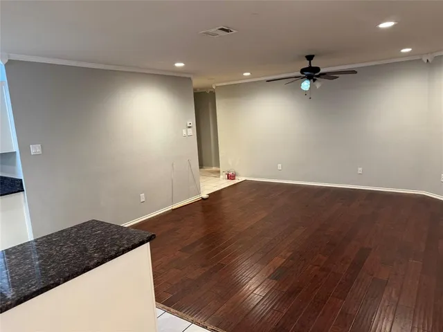 an empty room with wooden floor cabinet and a ceiling fan