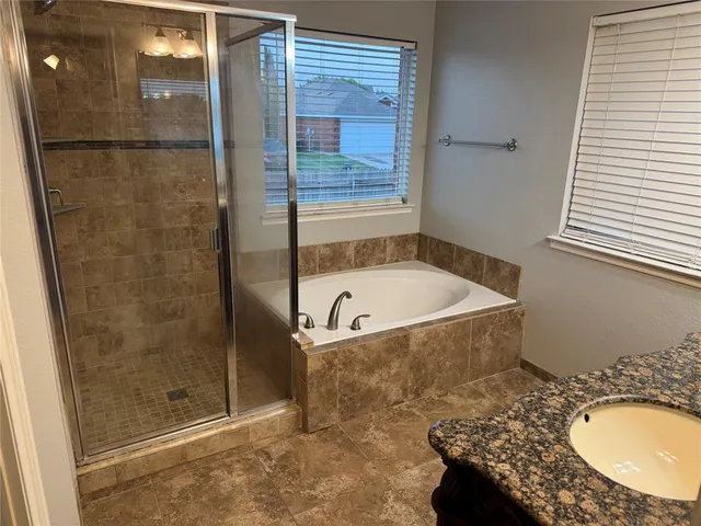 a bathroom with a granite countertop bathtub and shower