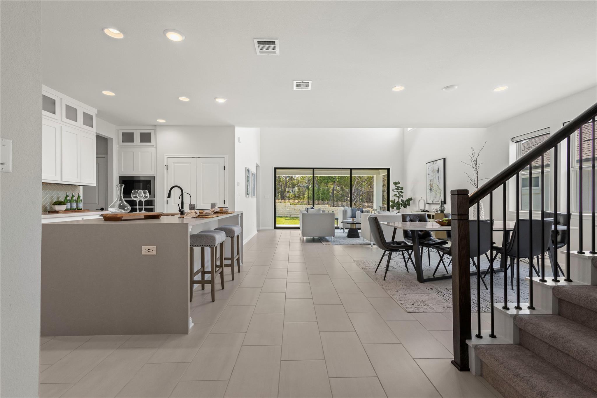 1128 Villa Rialto View Leander, TX 78641 - Photo 12 of 40 An open concept living area seamlessly connects a modern kitchen, dining space, and a family room overlooking nature.