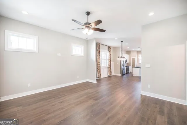 a view of a livingroom with a ceiling fan wooden floor and a ceiling fan