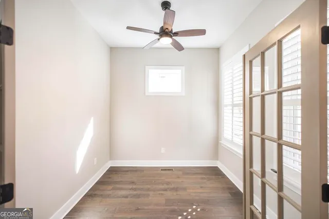 a view of empty room with wooden floor and fan