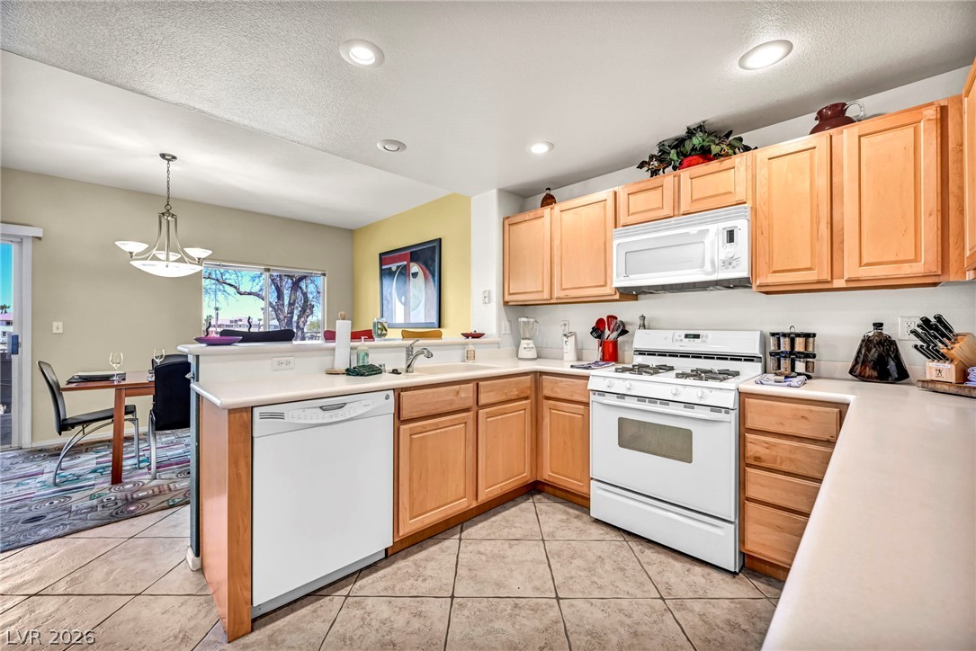 10730 Amber Ridge Drive, Unit 101 Las Vegas, NV 89144 - Photo 12 of 32 A well-appointed kitchen boasts ample cabinetry and essential appliances, seamlessly connecting to a cozy dining area.