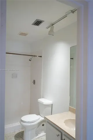 a white toilet sitting next to a bathroom sink and a shower