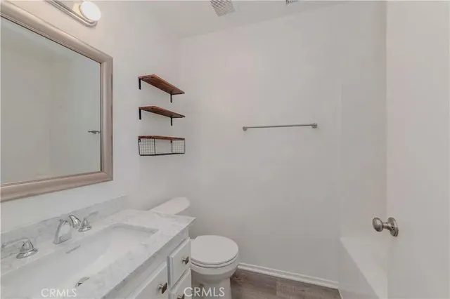 a bathroom with a granite countertop sink and a toilet