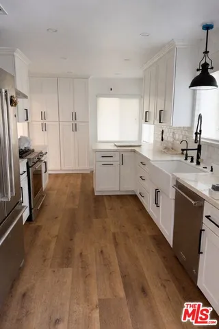 a large kitchen with a sink dishwasher stove and white cabinets