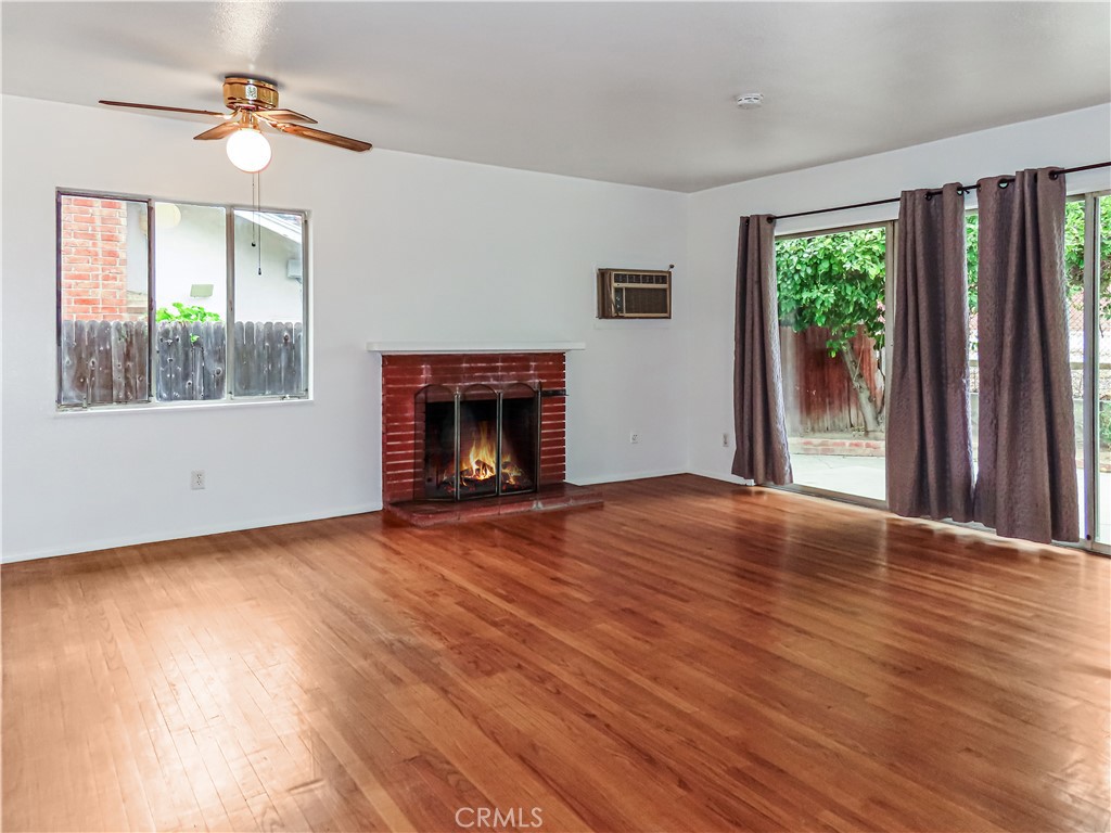 6688 Montclair Drive Riverside, CA 92504 - Photo 6 of 21 an empty room with windows fireplace and wooden floor