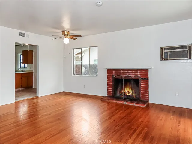 an empty room with wooden floor fireplace and windows
