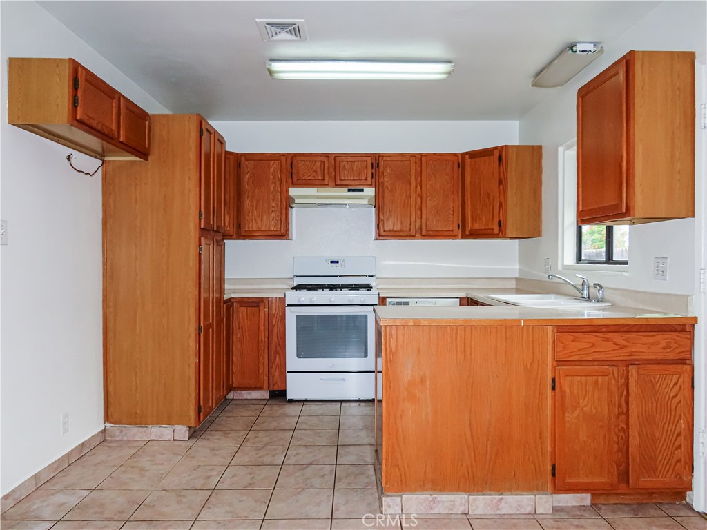 6688 Montclair Drive Riverside, CA 92504 - Photo 10 of 21 a kitchen with granite countertop a sink cabinets stainless steel appliances and a window