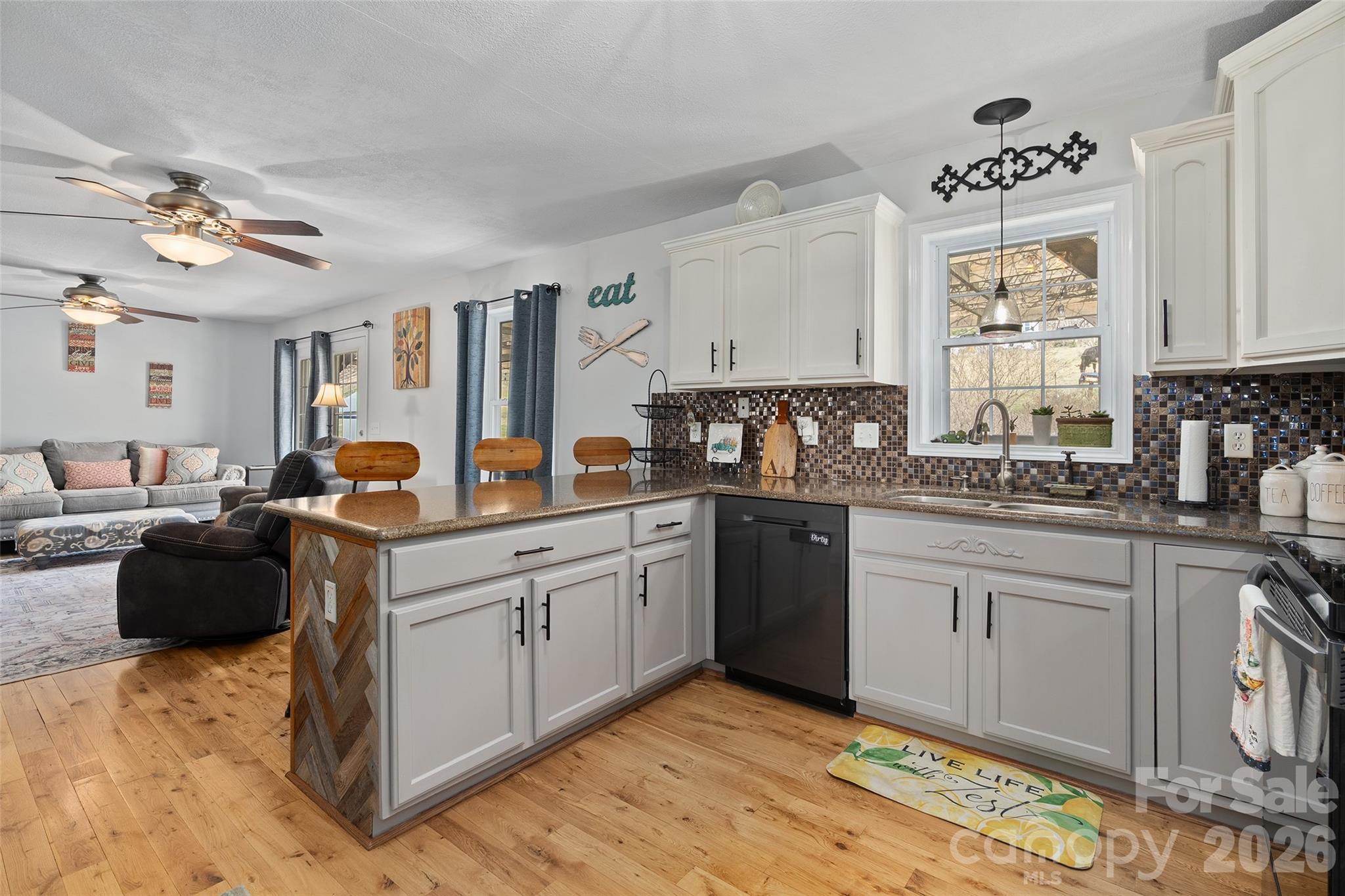 371 Ned Cove Road Waynesville, NC 28785 - Photo 17 of 44 a kitchen with stainless steel appliances granite countertop a sink dishwasher a stove and white cabinets with wooden floor