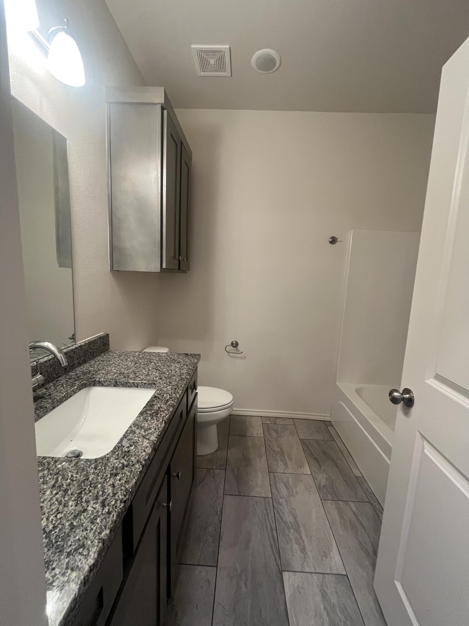 2611 136th Street Lubbock, TX 79423 - Photo 9 of 13 a bathroom with a granite countertop sink a toilet and a mirror