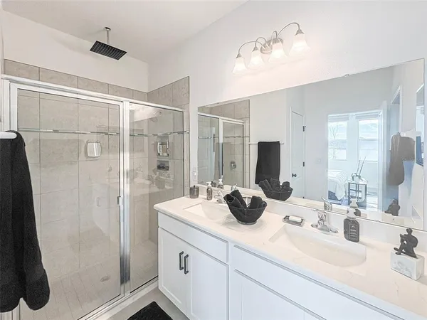 a bathroom with double vanity sink a mirror a glass door a shower and vanity