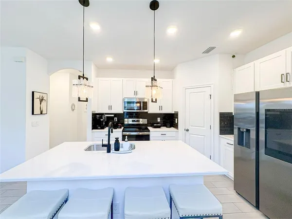 a kitchen with refrigerator and chairs