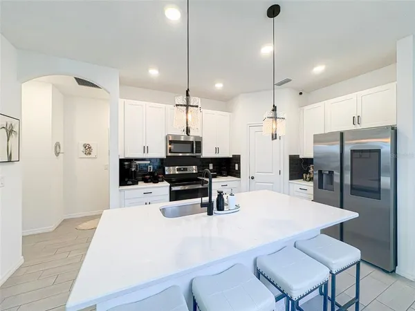 a kitchen with stainless steel appliances a refrigerator a stove a sink a dining table and chairs with wooden floor