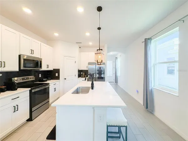a kitchen with stainless steel appliances kitchen island granite countertop a sink a stove and a refrigerator