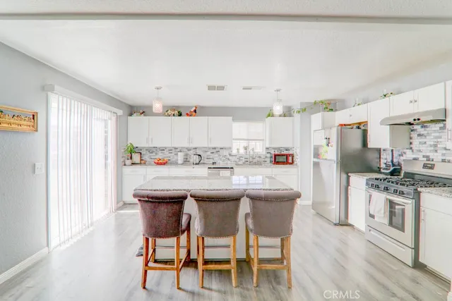 a kitchen with stainless steel appliances kitchen island granite countertop a table chairs and a refrigerator