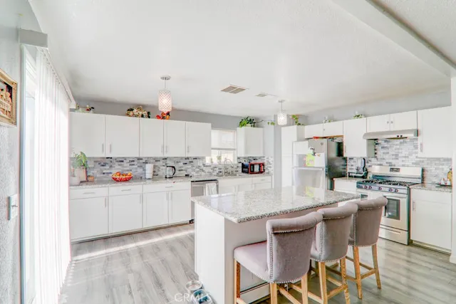 a kitchen with kitchen island a stove a table and chairs in it