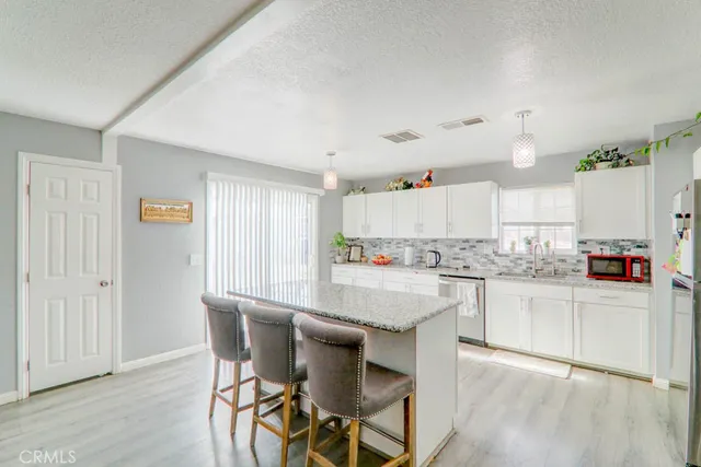 a kitchen with granite countertop white cabinets and stainless steel appliances