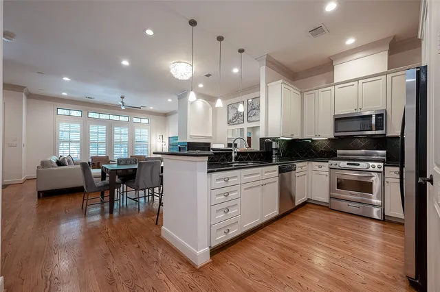 a kitchen with stainless steel appliances kitchen island granite countertop a stove a sink a refrigerator and a microwave