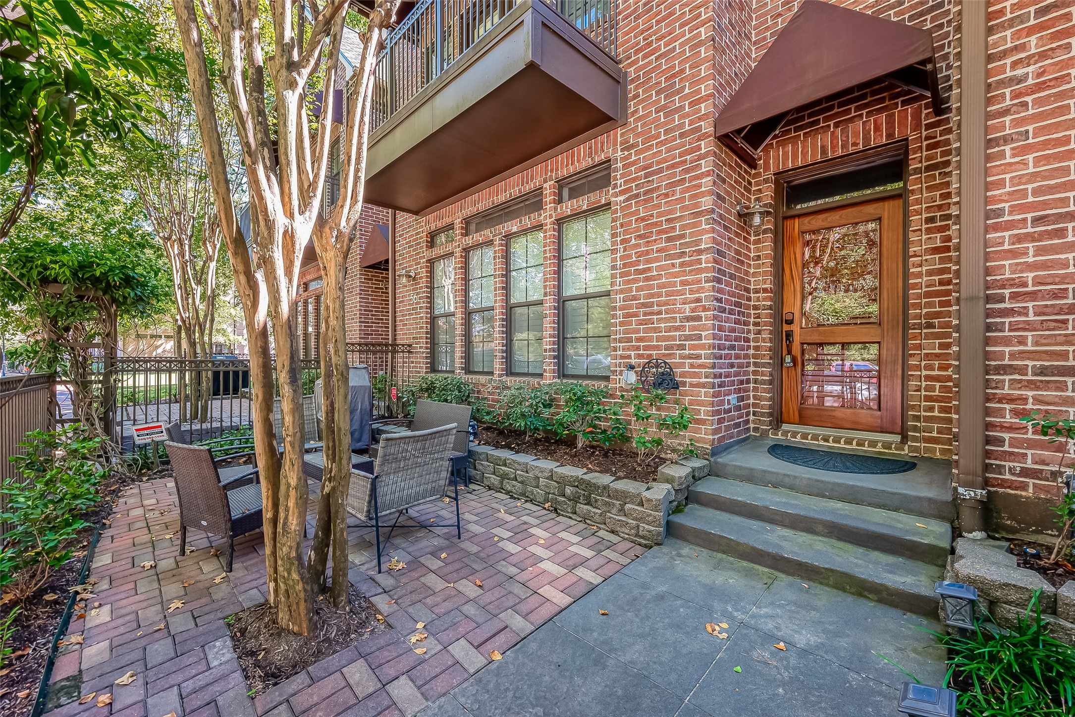 56 Riva Row The Woodlands, TX 77380 - Photo 3 of 36 a view of a brick house with a chairs and table in a patio