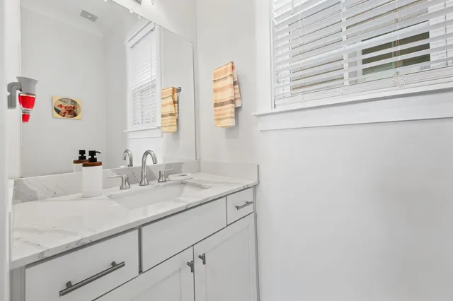 a bathroom with a granite countertop sink and a window