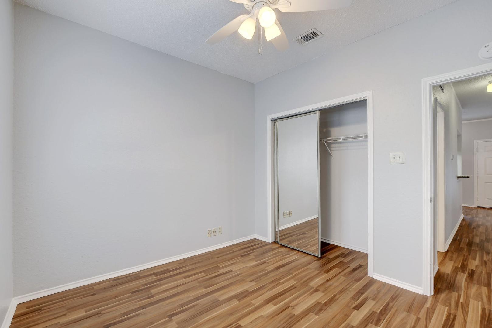 2804 Rio Grande Street, Unit 310 Austin, TX 78705 - Photo 14 of 22 A comfortable bedroom with wood-look flooring and a mirrored closet.
