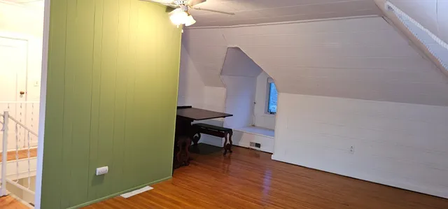 a view of a hallway with wooden floor and a bathroom
