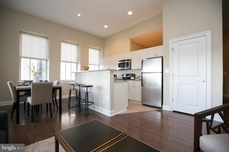 301 North Charles Street, Unit 1BR Baltimore, MD 21202 - Photo 44 of 48 a kitchen with stainless steel appliances granite countertop a refrigerator a stove a dining table and chairs with wooden floor